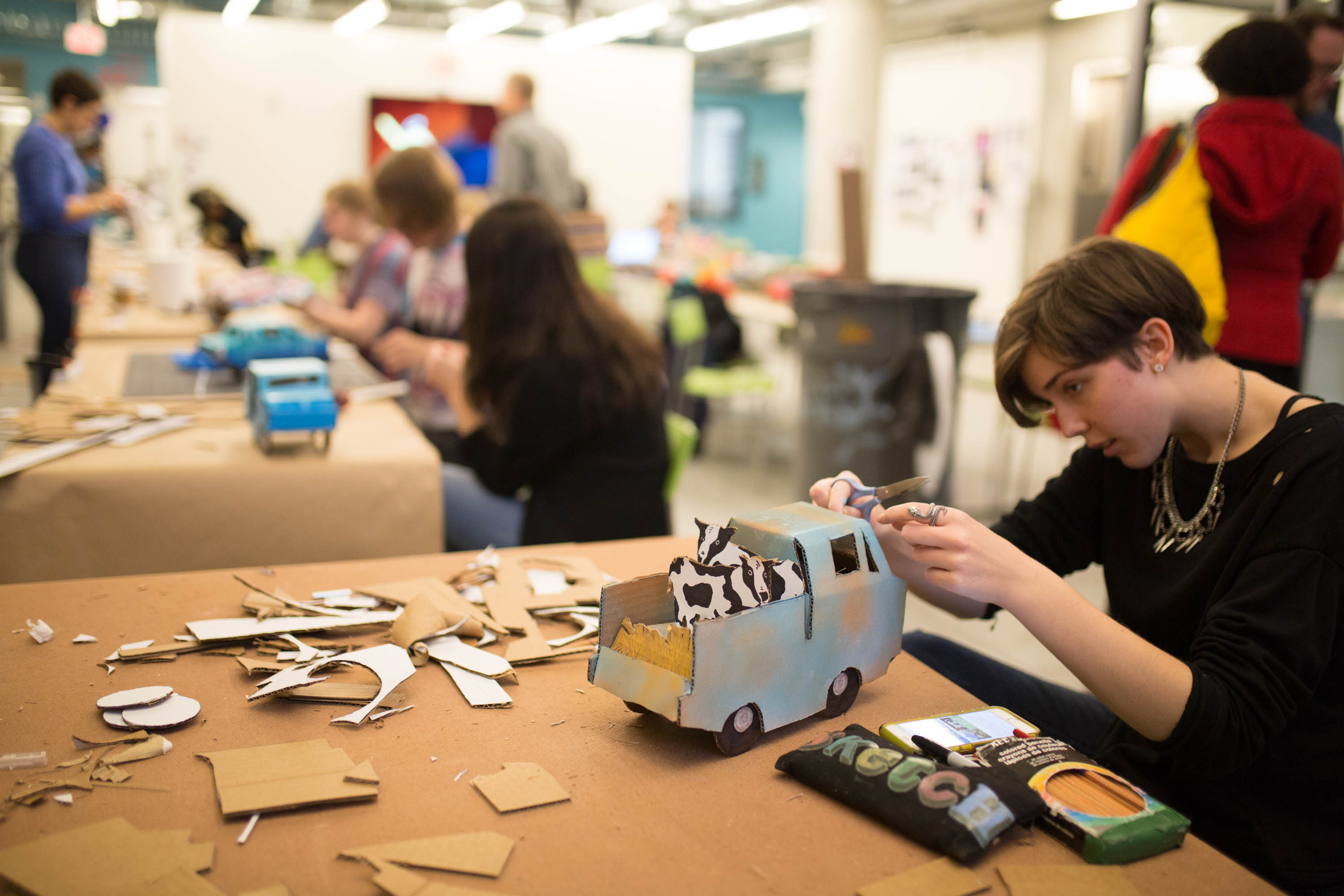 A student works on a farm-themed truck with cows in the back.