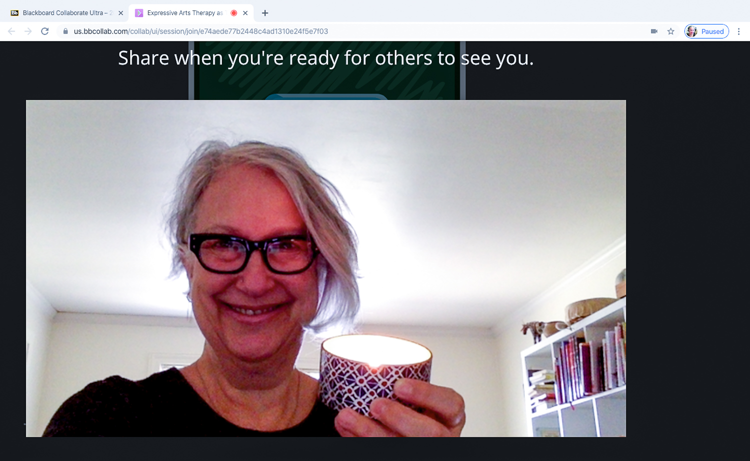 Screenshot of Ara Parker holding up a candle during an online class