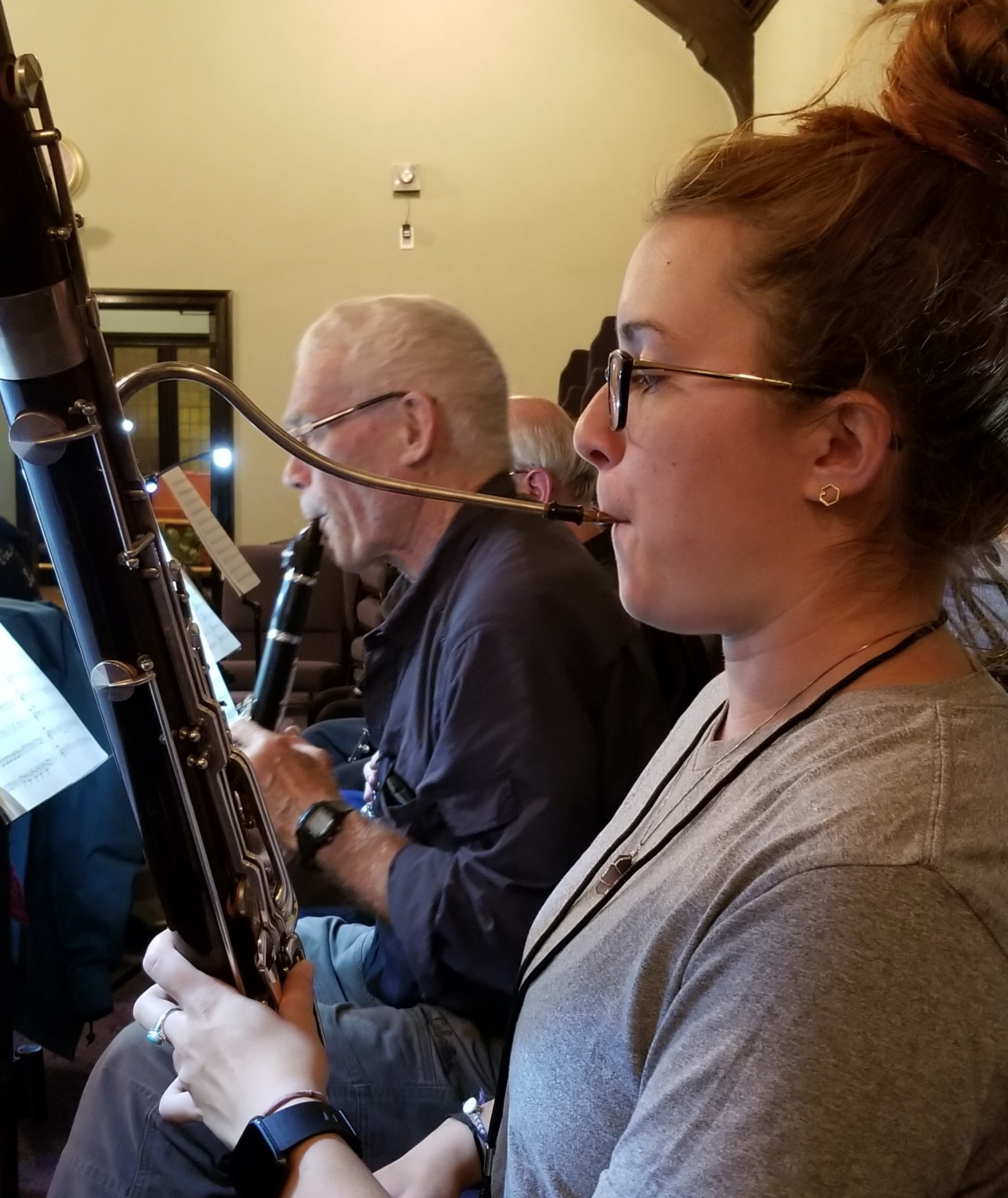 A woman in an orchestra playing a bassoon.