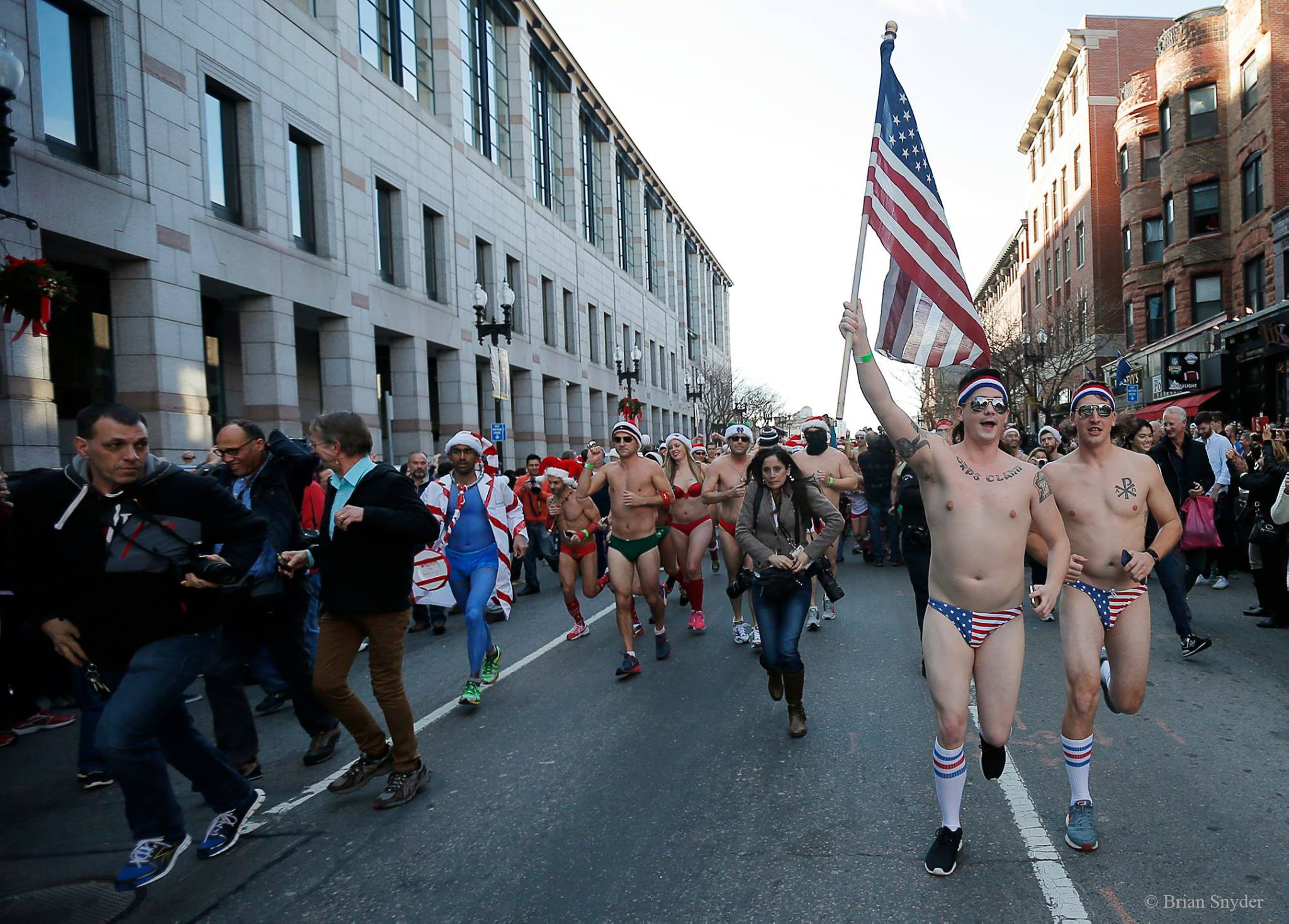 Parade of people in Speedos with Faith Ninivaggi in the center with cameras