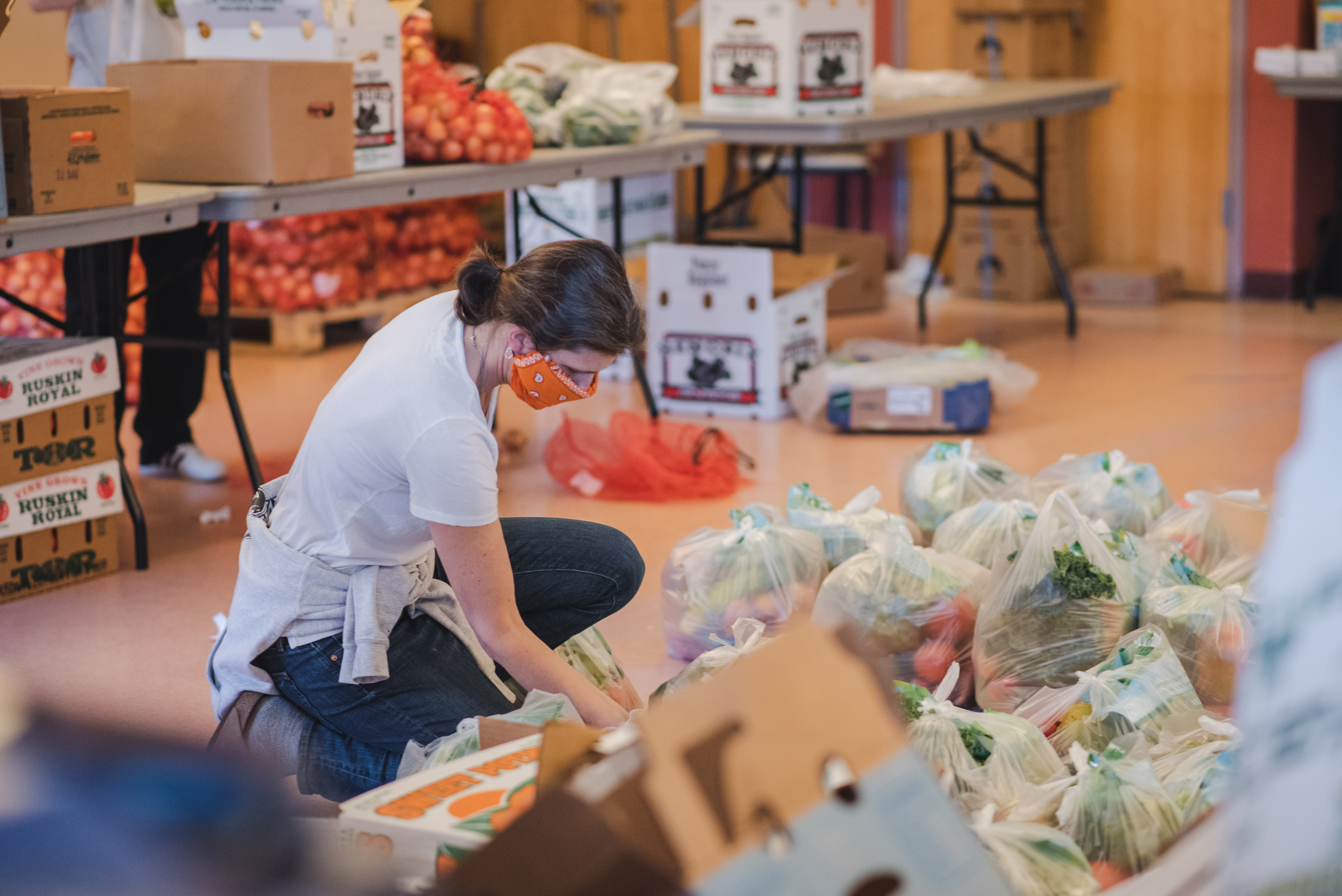 Woman with a mask knealing to look at bagged food