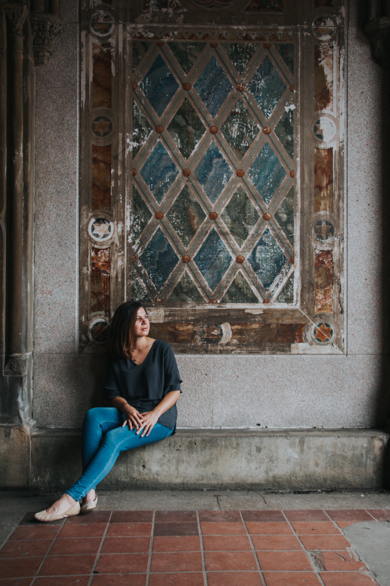 Ingrid Strobe sitting on a stoop with a rustic wall behind her