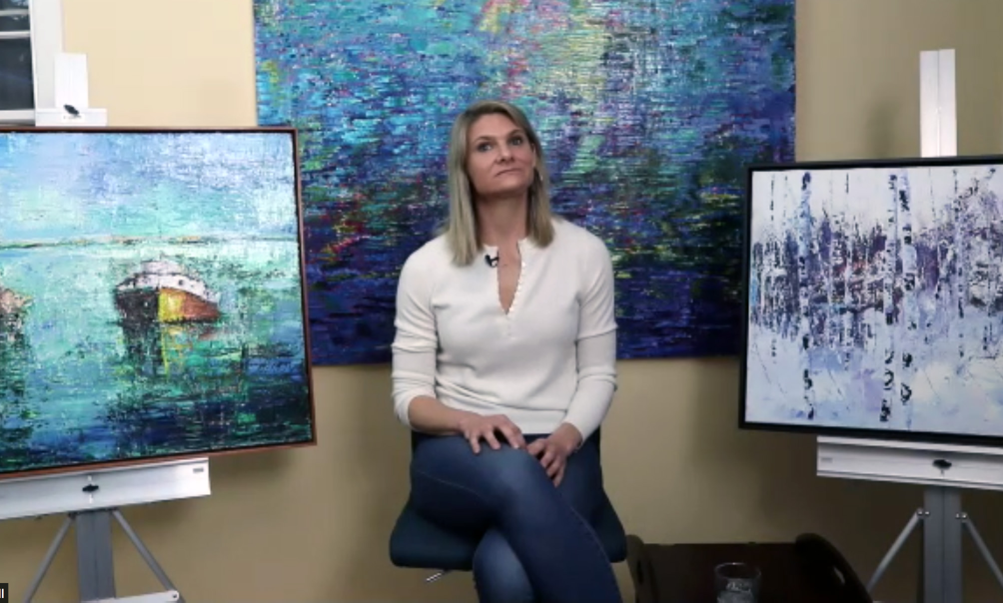 Julia Powell pictured in her studio surrounded by three paintings