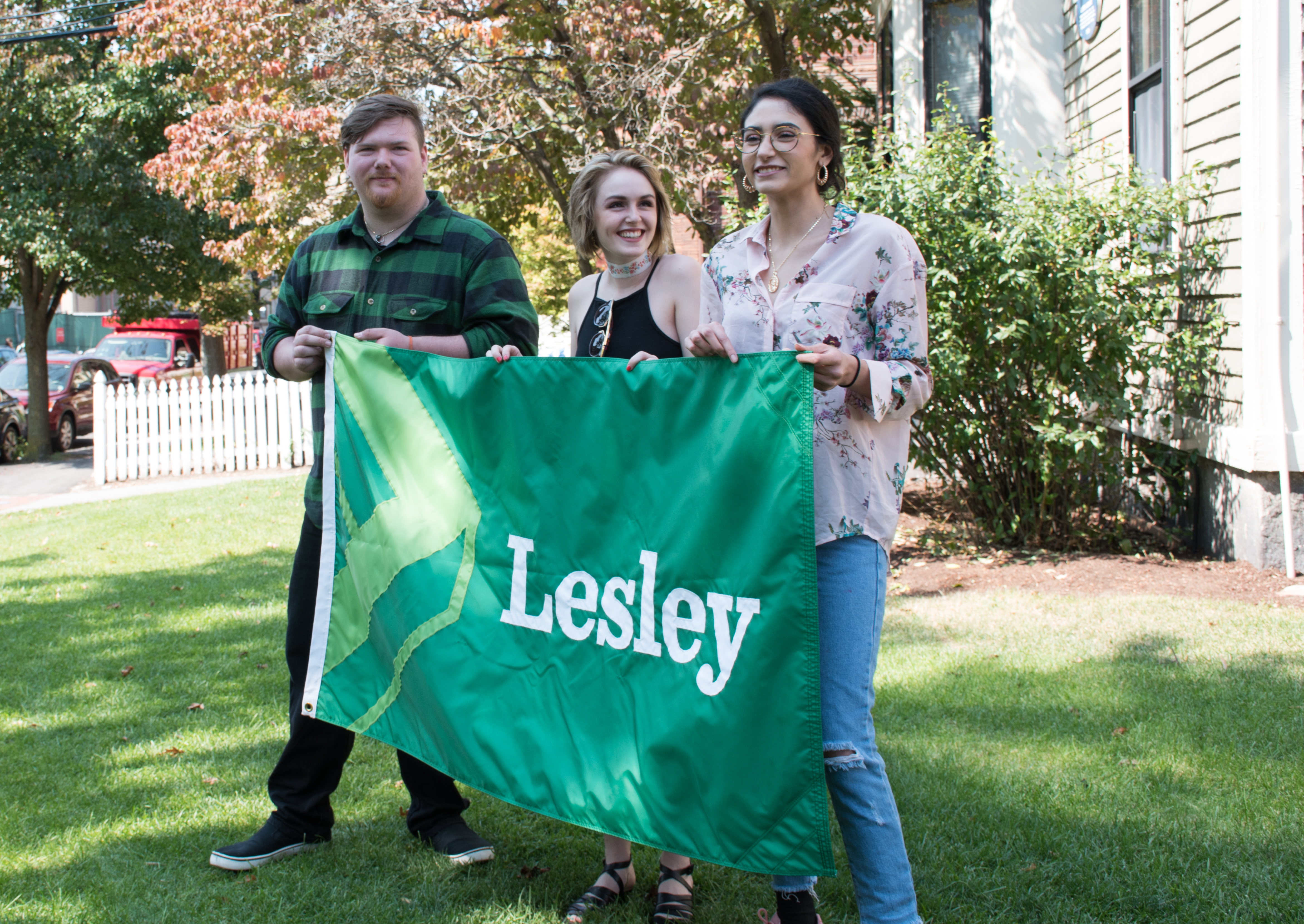 Students Michael Coleman, Raine Ferrin and Christine Lopez Corado hold the new Lesley flag that they designed.