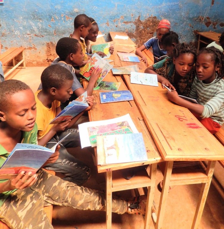 Children from Ethiopia sit at a wooden table in a classroom with blue-painted walls.