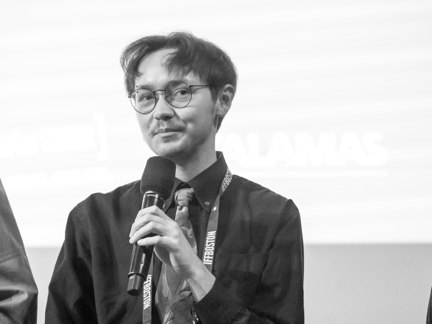 Thomas Tague-Bleau black and white photo, holding a microphone