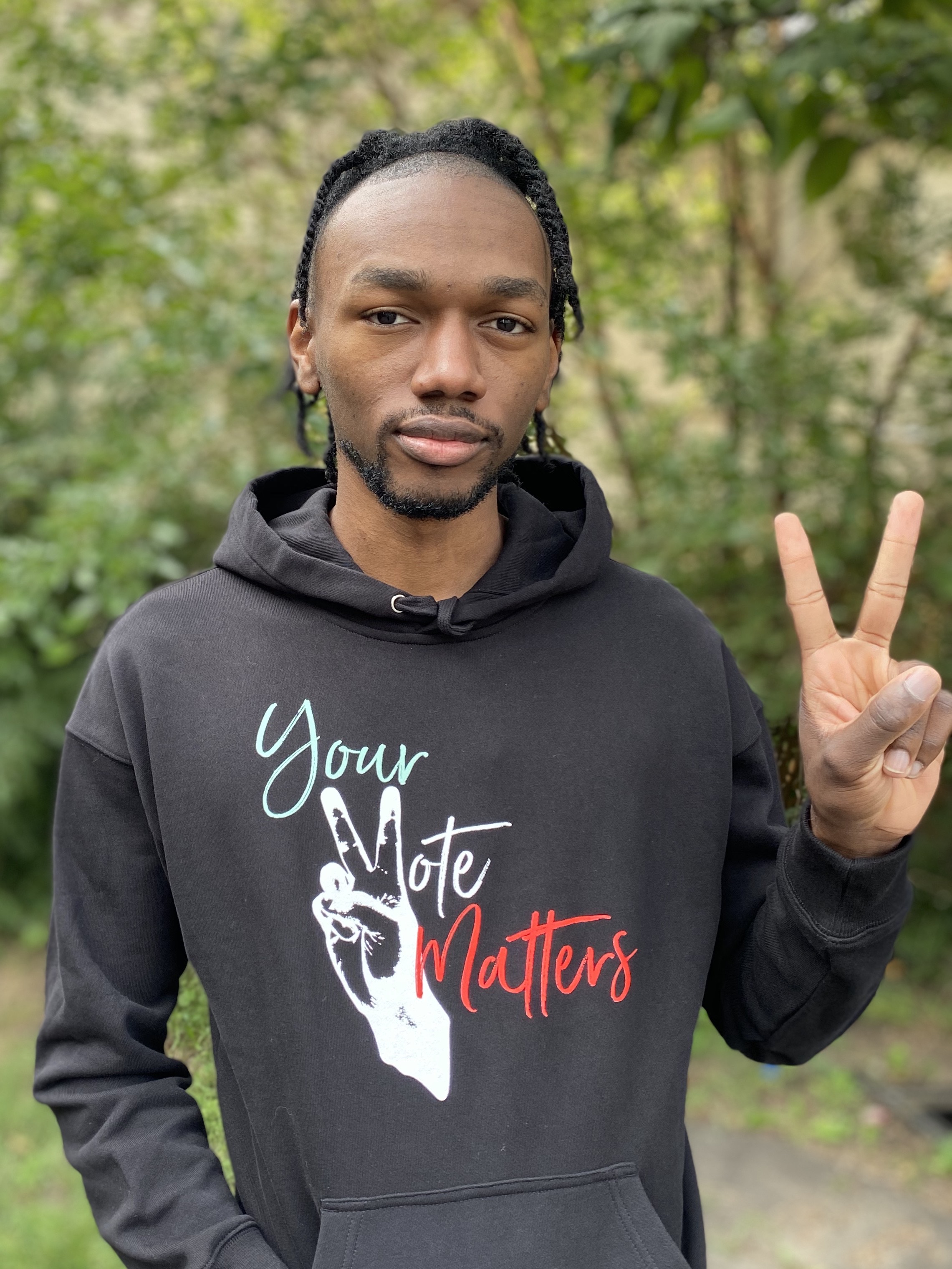 Trevonne Deveaux wearing the hoodie he designed, flashing peace sign