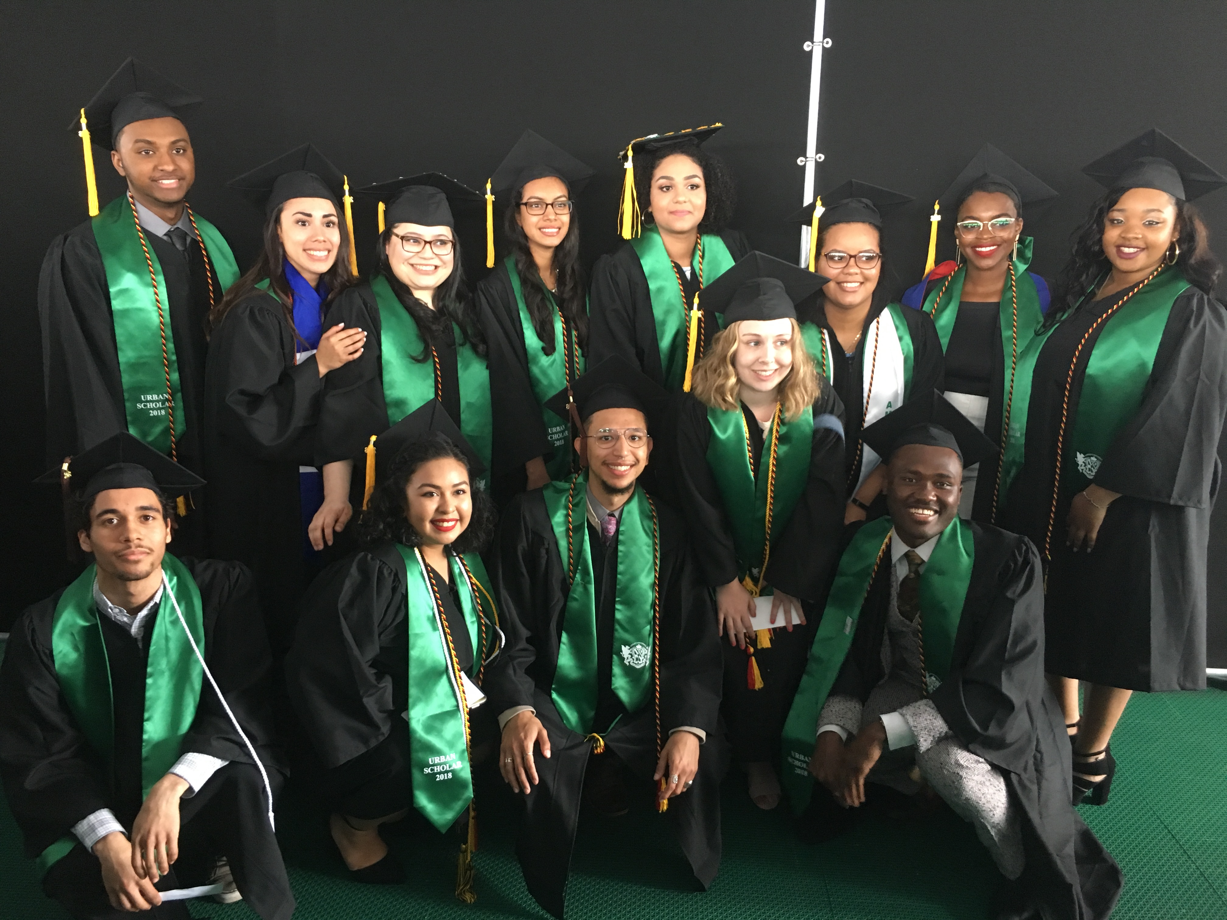 The USI graduates in cap and gown, all wear a green sash.