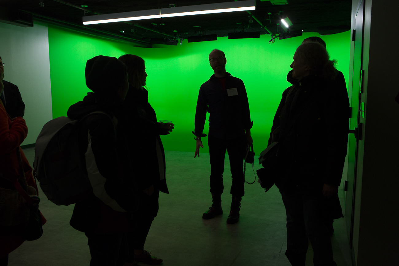 People silhouetted against the lit green room.