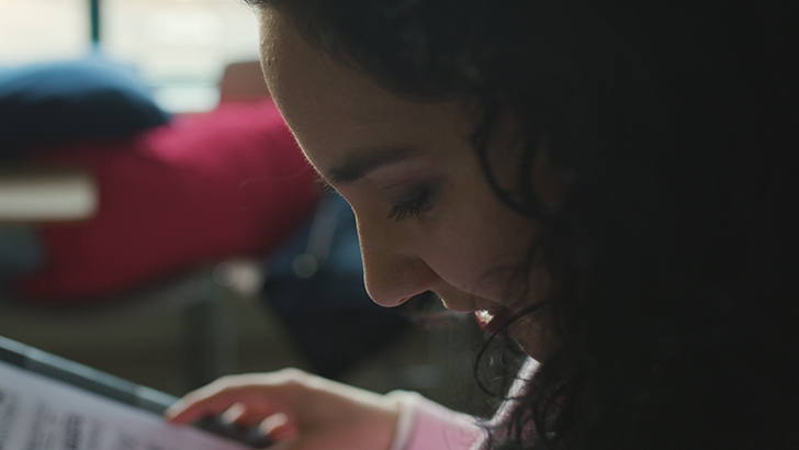 Woman with dark curly hair leaning over looking at a piece of sheet music.