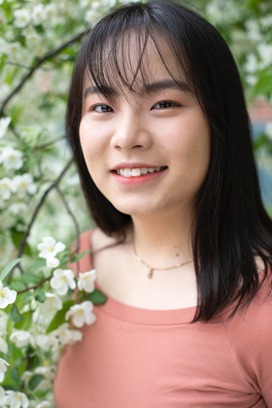 YiRan Li standing amid a flowering tree.