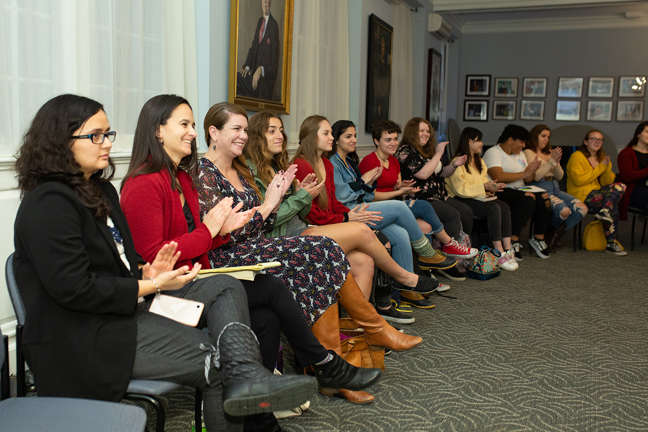 A group of students seated in Alumni Hall applauding