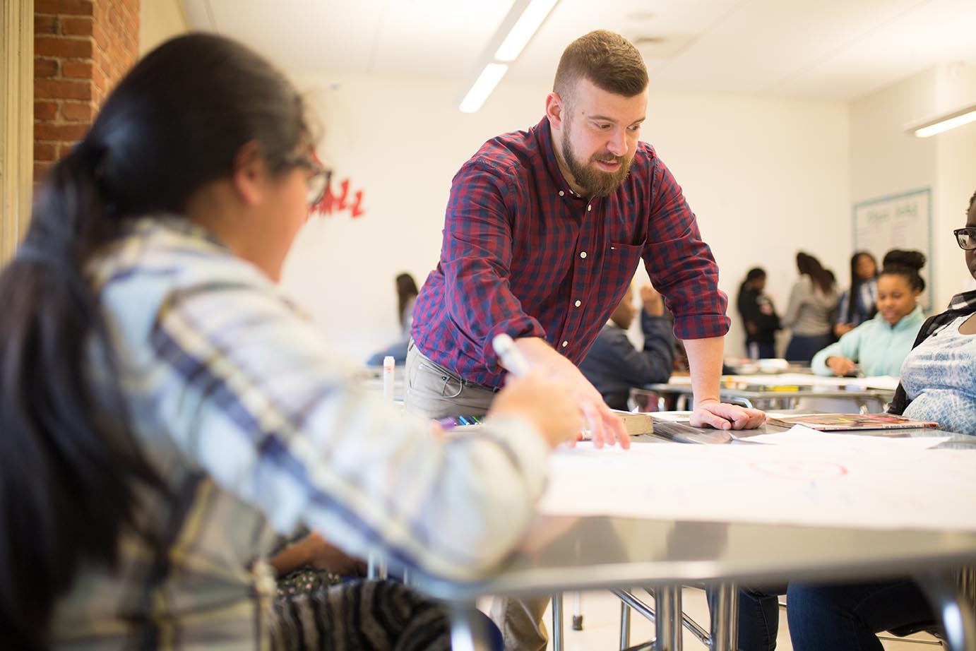 Alumnus Beau Morimando Teaching Students at a Desk