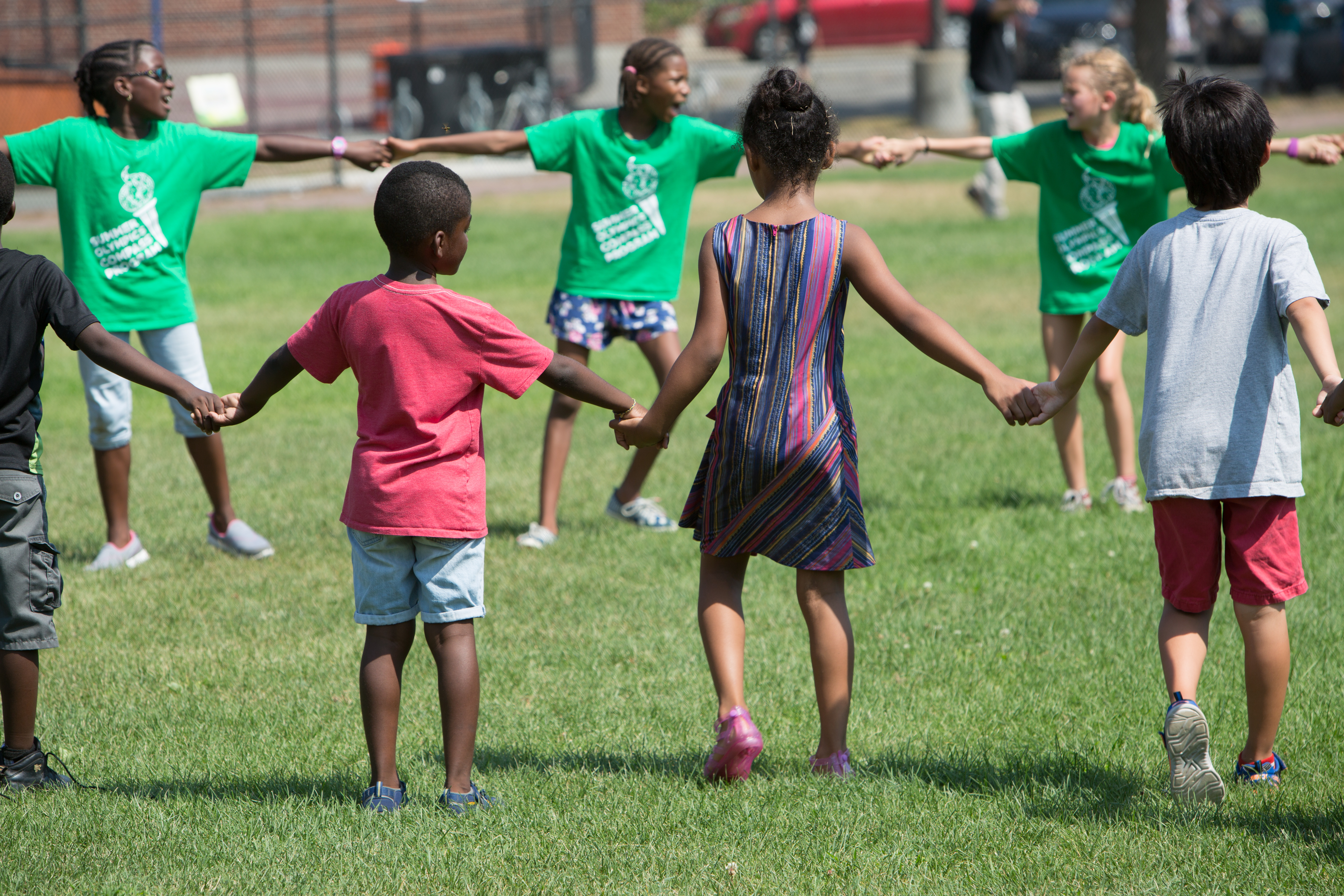 Small children outside on playground, holding hands in a circle