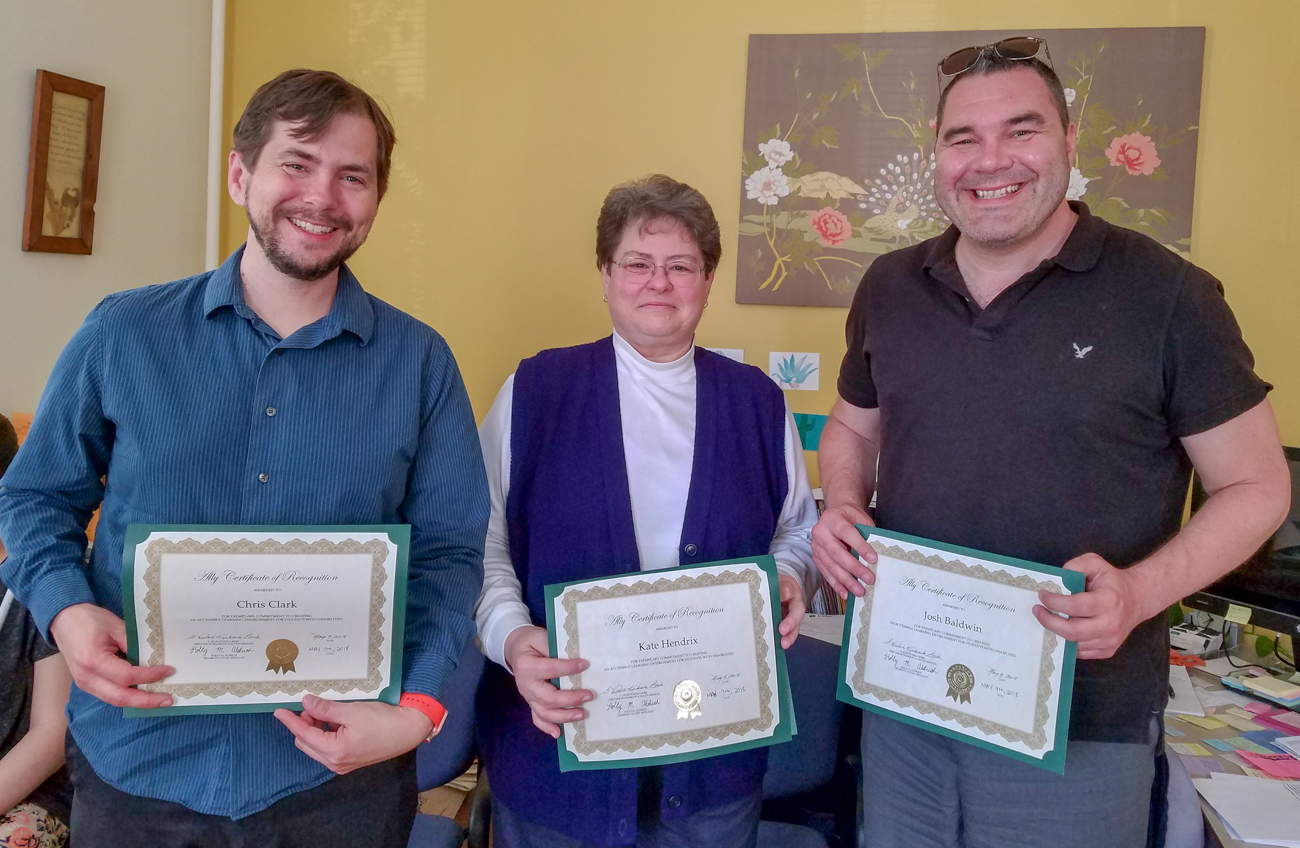 Chris Clark, Kate Hendrix and Josh Baldwin stand in a row and smile while holding their awards.