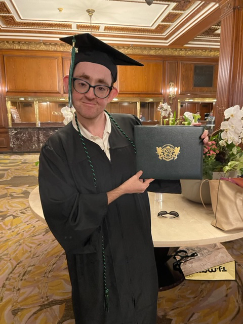 Daniel Dubinsky in academic regalia holding Lesley degree