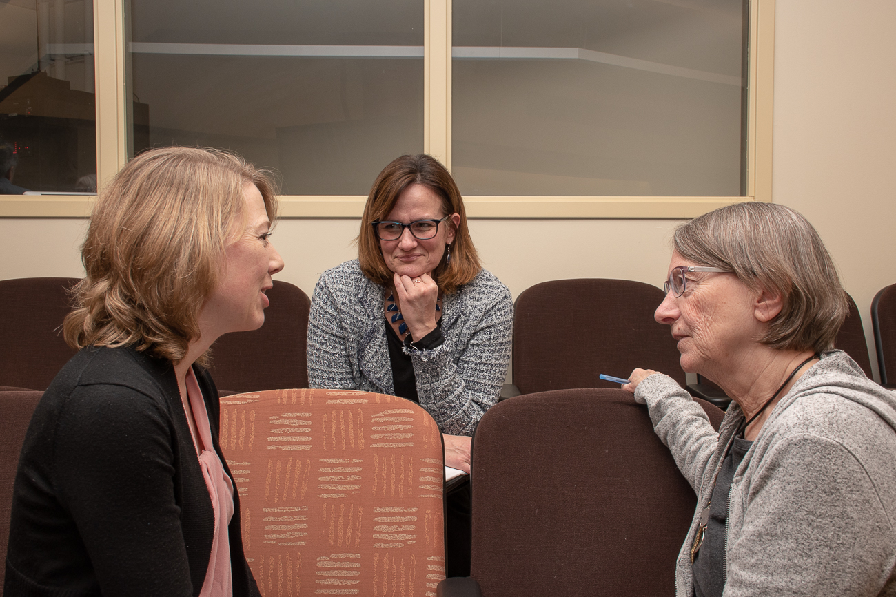 Three women talk to each other.