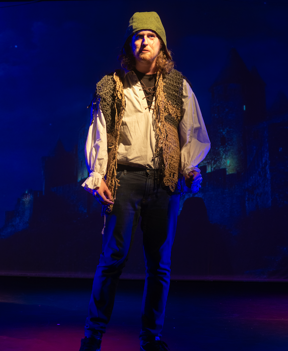 An actor on stage in Marran Theater dress in a Shakespearean costume in a production of Macbeth