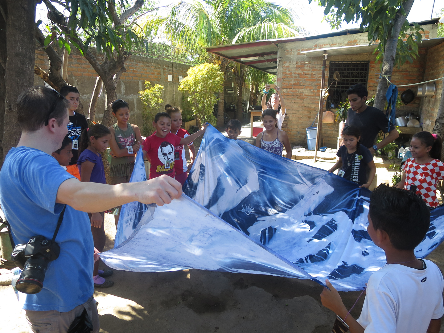 children standing in circle holding sheet with their handprints on it