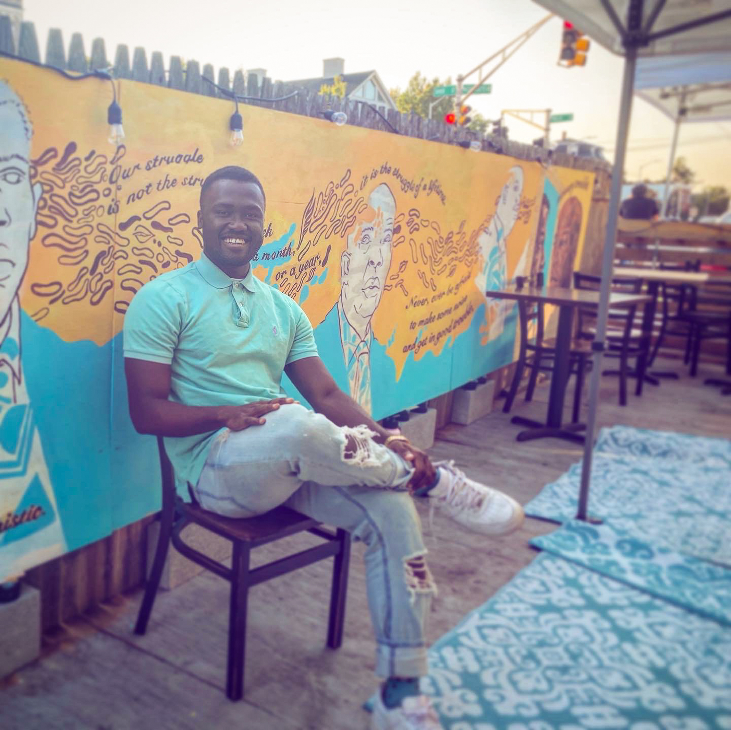 Rocky Cotard sitting in a chair in front of his mural at Urban Hearth