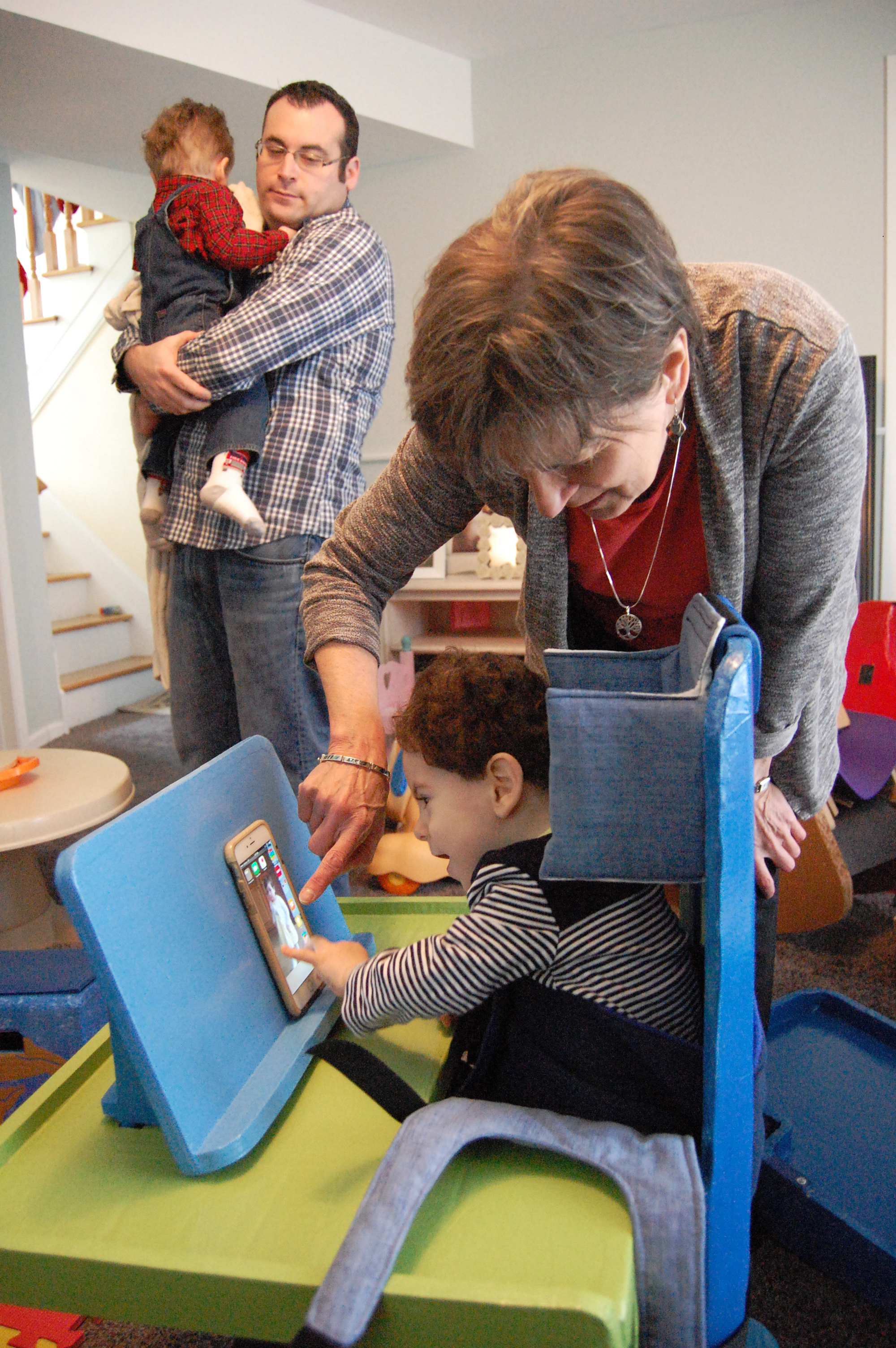 male toddler using iphone with the help of an adult woman