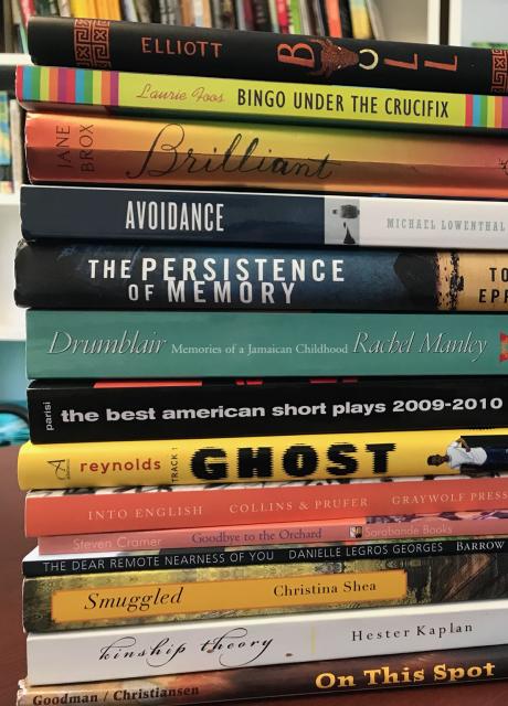 Stack of books on a table with white shelving in the background