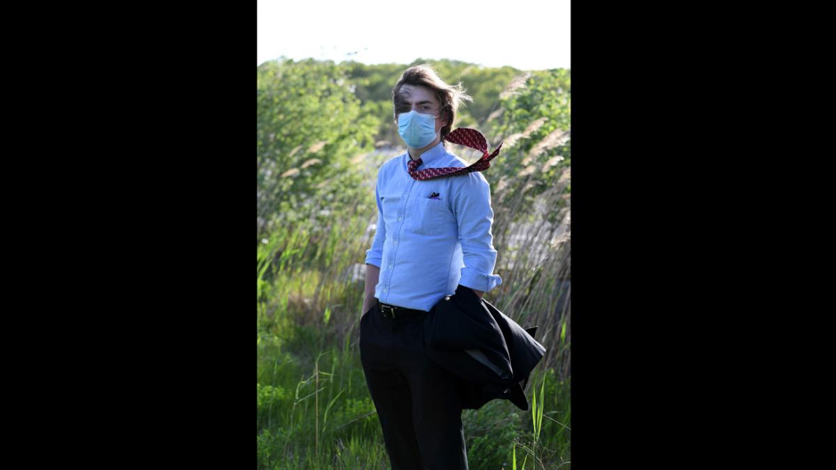 Boy dressed up for the prom with the wind blowing his tie