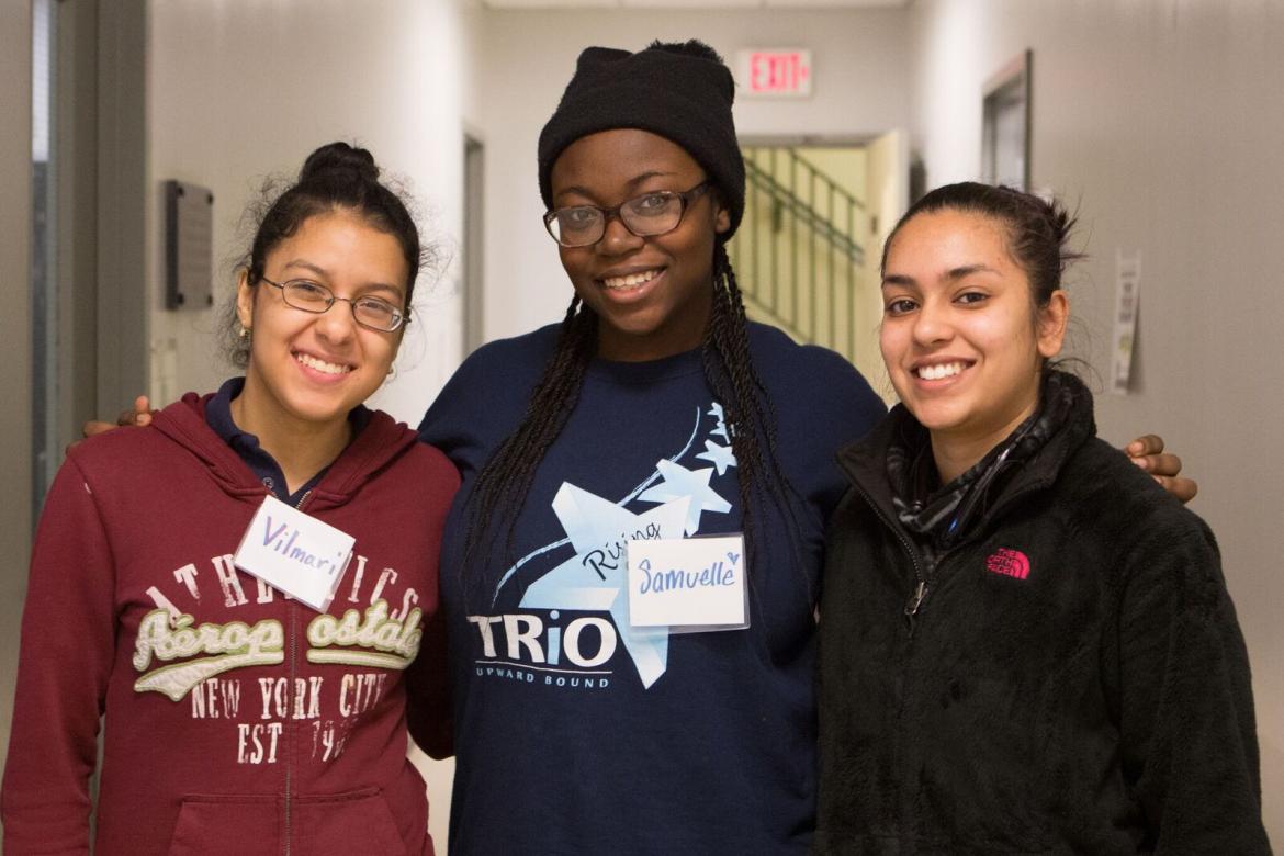 Three girls stand in the hallway. 