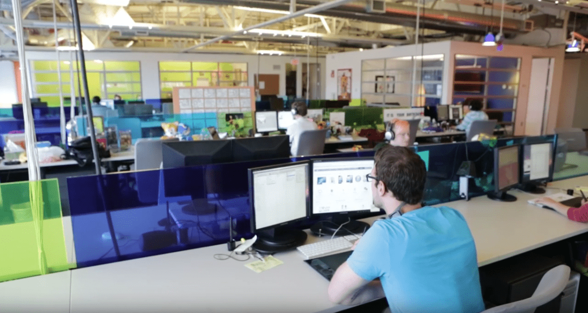 male student sits at desk working on computer in large open area office space