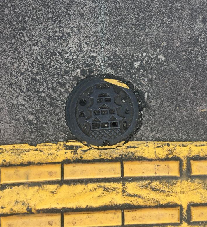 Tiny manhole cover with traditional building.