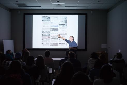 artist aaron kach presents a slideshow of work to students