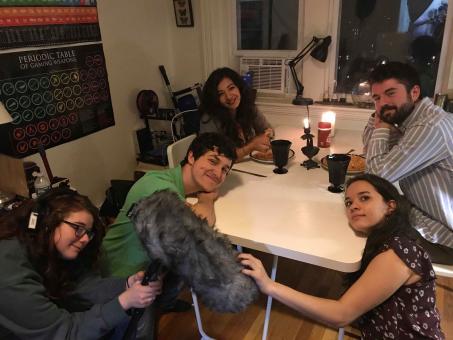 people sit around a table between takes on the set of the movie "Know Your Roll"