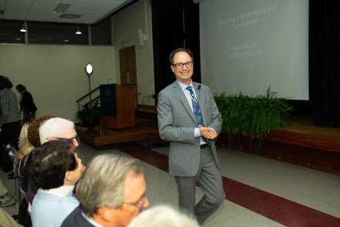 Chair of the Board Hans Strauch standing in front of the stage in Washburn Auditorium