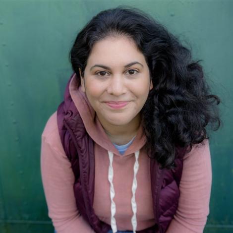 Photograph of Sara Farizan leaning forward smiling at the view. 