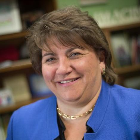 Headshot photograph of Interim Provost Deanna Yameen smiling at the camera wearing a blue blazer.