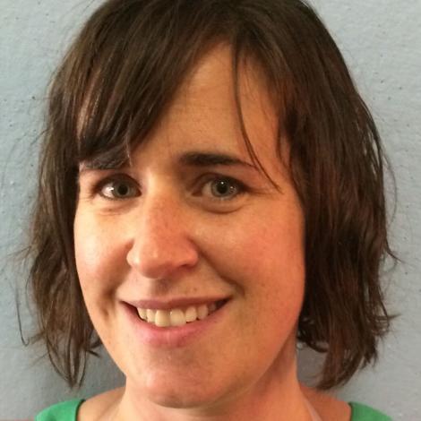 Photo of staff member Sarah Hugenberger smiling in front of white wall