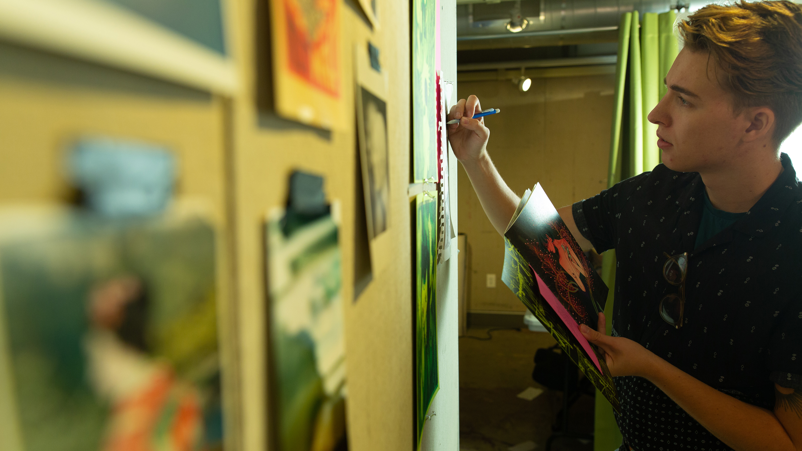 student looks at illustration work tacked to wall